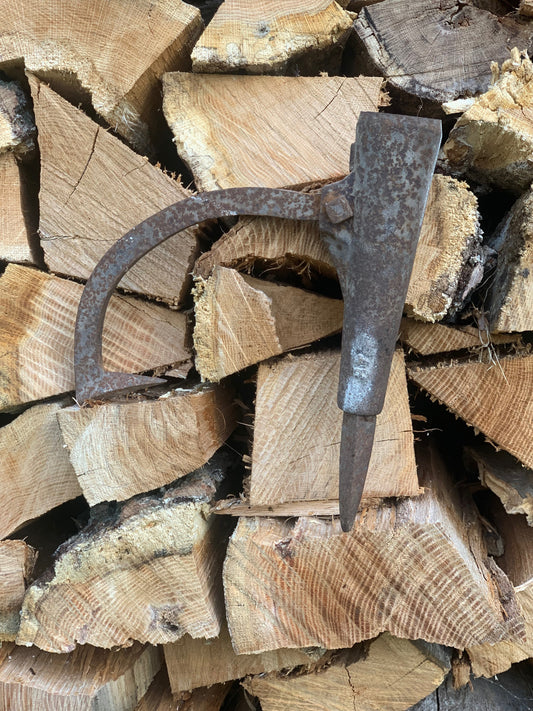 Steel peavy head sitting on a plie of cut wood. 