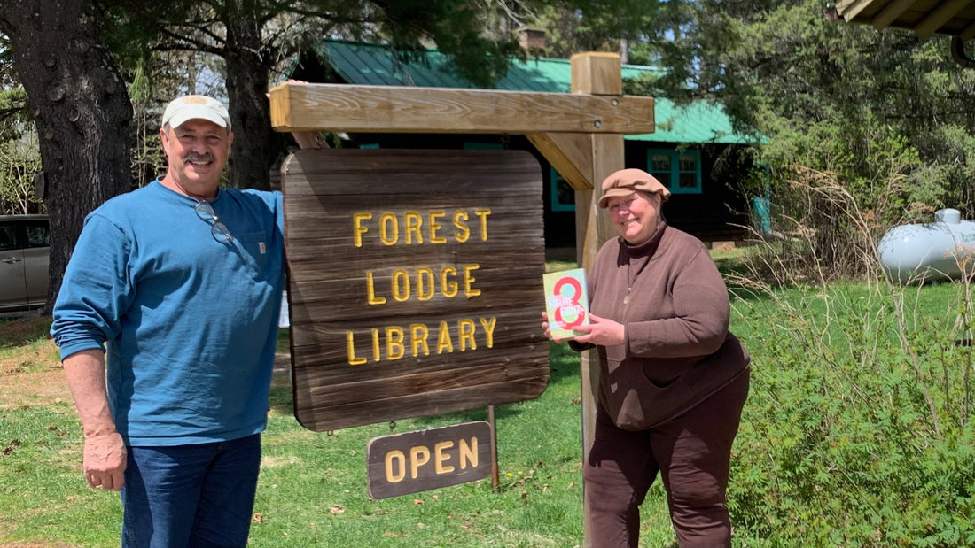 Jeff Nania standing next to Forest Lodge Library sign. Library director standing on other side. 